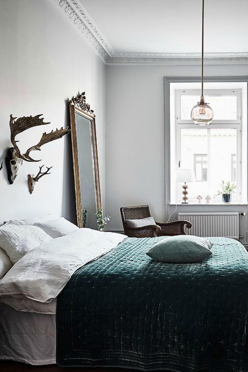 Ylellisesti sisustettu makuuhuone, jonka painopiste on peuran sarvet sängyn päädyssä 